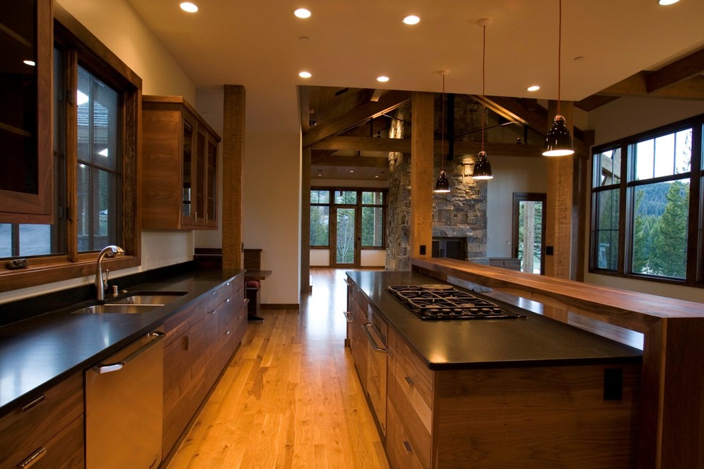 Trendy light wood floor eat-in kitchen photo with an undermount sink, flat-panel cabinets, medium tone wood cabinets, granite countertops, black backsplash, stone slab backsplash, stainless steel appliances and an island