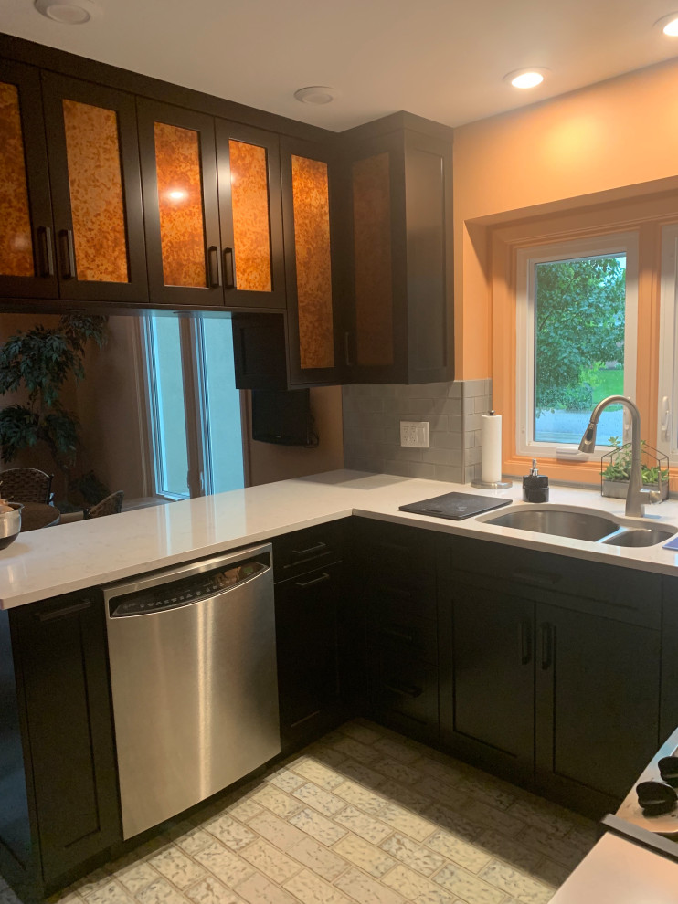 Inspiration for a small transitional u-shaped ceramic tile and multicolored floor enclosed kitchen remodel in Indianapolis with a double-bowl sink, recessed-panel cabinets, black cabinets, quartz countertops, gray backsplash, ceramic backsplash, stainless steel appliances, a peninsula and gray countertops
