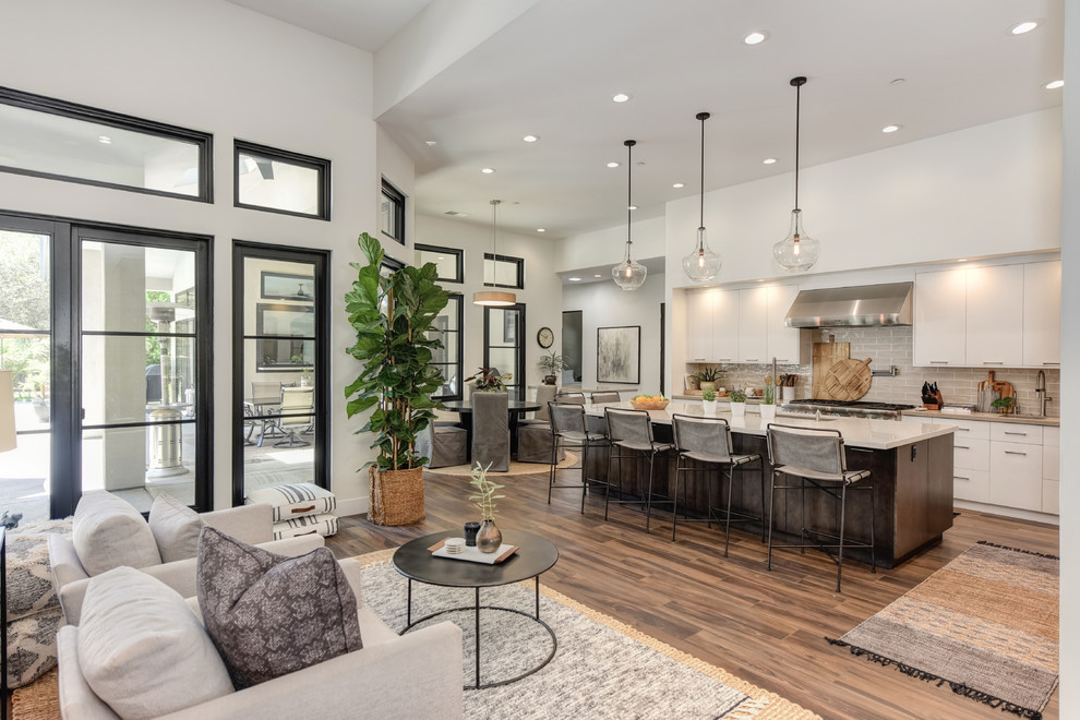 This is an example of a contemporary u-shaped open plan kitchen in Sacramento with flat-panel cabinets, white cabinets, beige splashback, subway tile splashback, stainless steel appliances, with island, brown floor, beige benchtop, an undermount sink, quartz benchtops and dark hardwood floors.