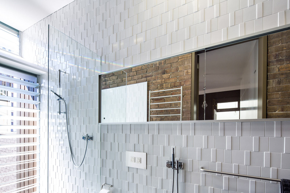 This is an example of a mid-sized modern master bathroom in Sydney with a wall-mount sink, flat-panel cabinets, an open shower, white tile, porcelain tile, white walls and porcelain floors.