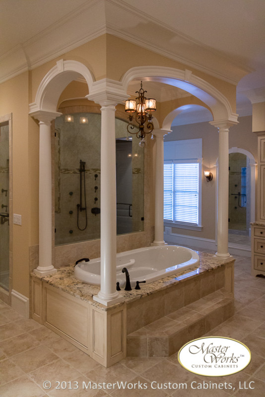 Inspiration for an expansive traditional master bathroom in Raleigh with beaded inset cabinets, distressed cabinets, beige tile, granite benchtops, a hot tub, a double shower, a one-piece toilet, mosaic tile, beige walls, porcelain floors and a drop-in sink.