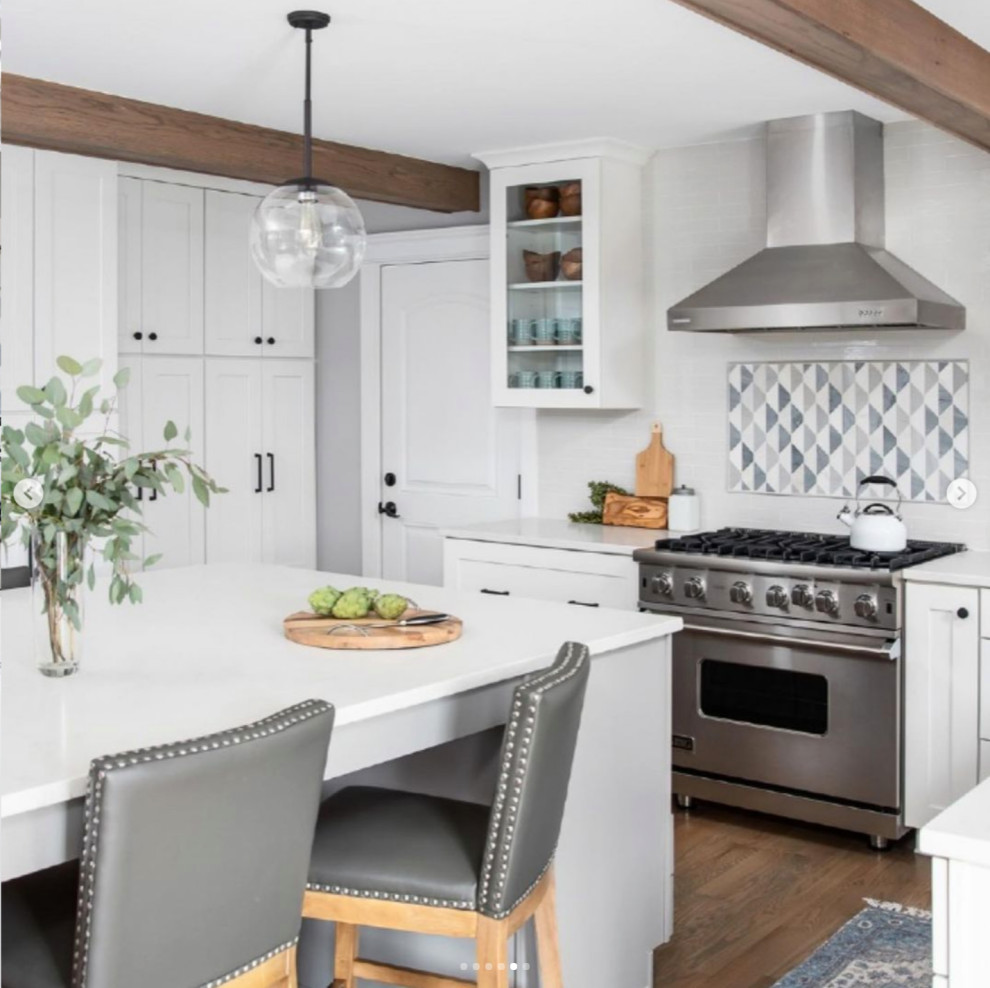 Design ideas for a large country eat-in kitchen in Chicago with a farmhouse sink, white splashback, stainless steel appliances, light hardwood floors, with island, brown floor and exposed beam.