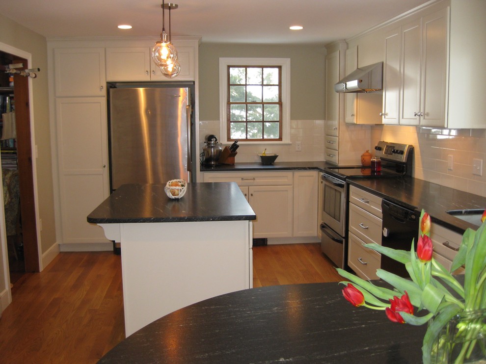 Transitional l-shaped medium tone wood floor eat-in kitchen photo in Boston with an undermount sink, shaker cabinets, white cabinets, quartz countertops, white backsplash, ceramic backsplash, stainless steel appliances, an island and black countertops