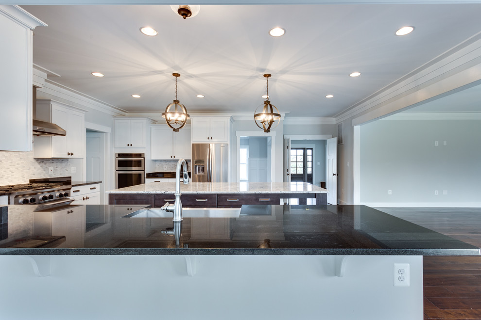 Inspiration for a large transitional u-shaped kitchen in DC Metro with a farmhouse sink, flat-panel cabinets, granite benchtops, grey splashback, stainless steel appliances, medium hardwood floors and with island.