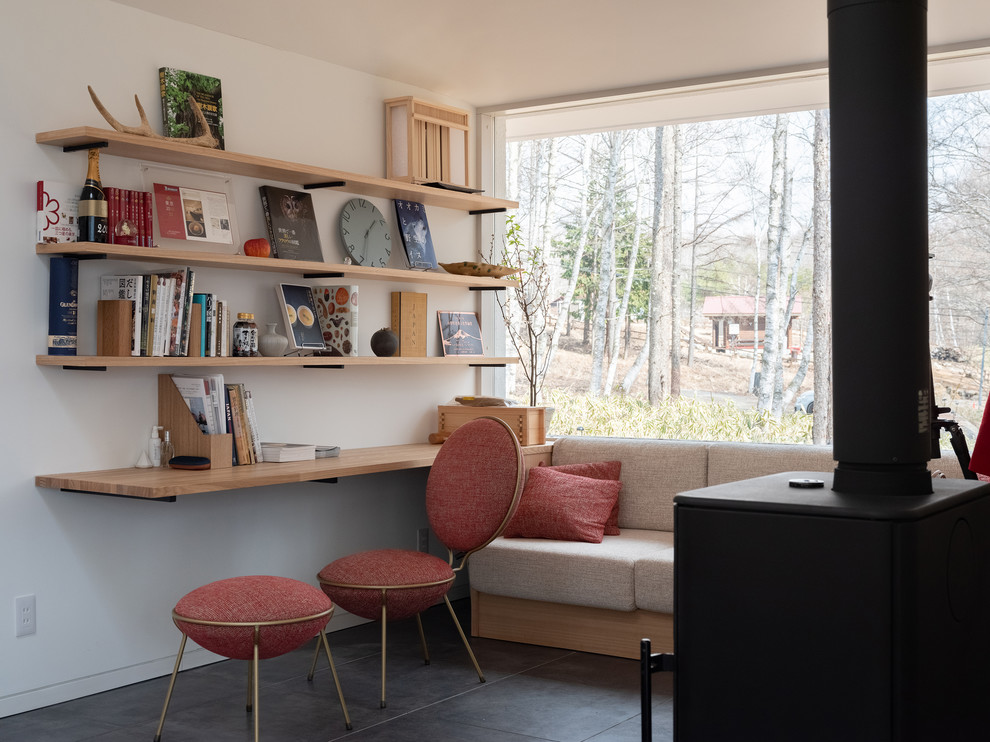 Photo of a modern home office in Tokyo with white walls, a built-in desk and black floor.