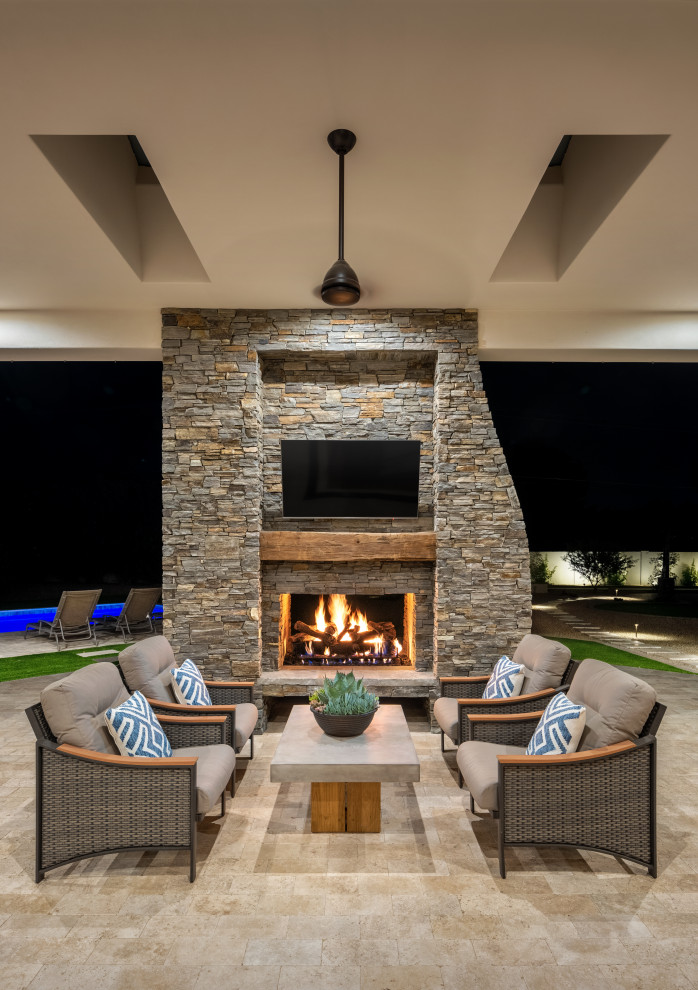 This is an example of a mid-sized transitional backyard patio in Phoenix with with fireplace, tile and a roof extension.