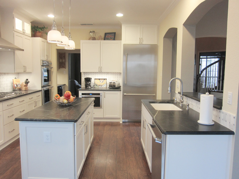 Large transitional dark wood floor eat-in kitchen photo with white cabinets, an island, an undermount sink, recessed-panel cabinets, white backsplash and stainless steel appliances