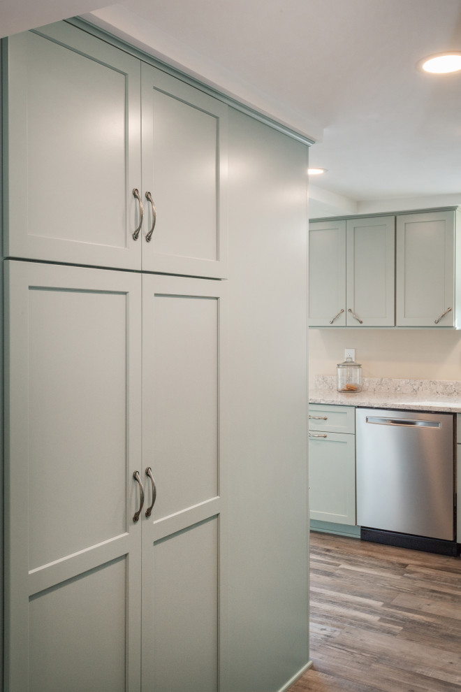 Example of a small transitional l-shaped vinyl floor and brown floor enclosed kitchen design with an undermount sink, shaker cabinets, green cabinets, quartz countertops, stainless steel appliances, a peninsula and gray countertops