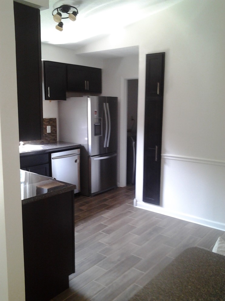 Mid-sized transitional l-shaped porcelain tile enclosed kitchen photo in Indianapolis with a drop-in sink, shaker cabinets, dark wood cabinets, granite countertops, brown backsplash, glass tile backsplash, stainless steel appliances and no island