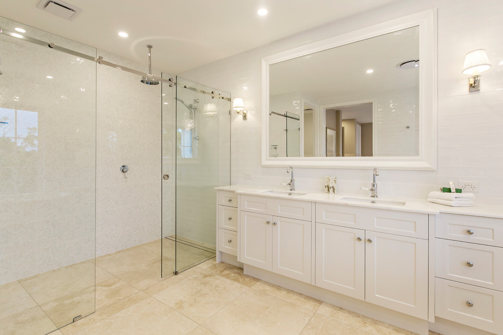 This is an example of a large traditional master bathroom in Gold Coast - Tweed with shaker cabinets, white cabinets, a freestanding tub, an alcove shower, white tile, subway tile, marble floors, an integrated sink, marble benchtops, beige floor and a sliding shower screen.