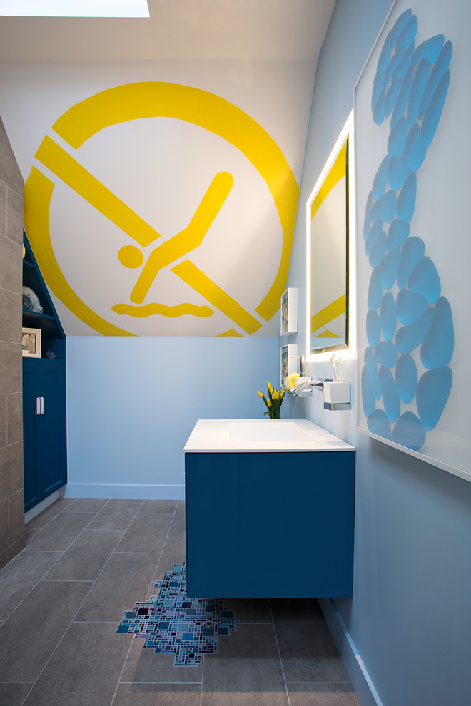 This is an example of a small modern kids bathroom in San Francisco with a wall-mount sink, furniture-like cabinets, solid surface benchtops, an open shower, a one-piece toilet, blue tile, glass tile, blue walls and porcelain floors.