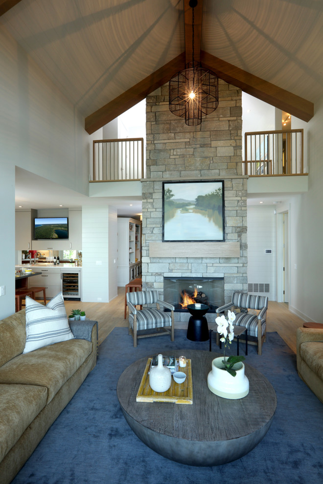 Inspiration for a mid-sized traditional open concept living room in Other with white walls, light hardwood floors, a two-sided fireplace, a stone fireplace surround, a wall-mounted tv and brown floor.