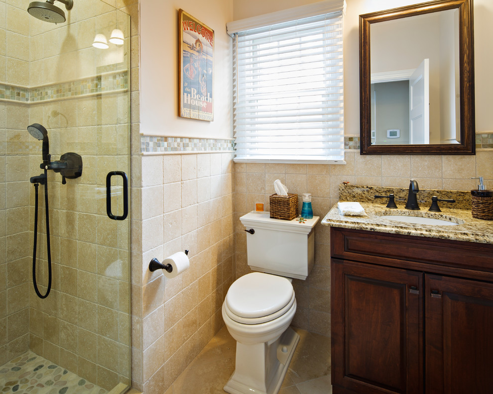 Inspiration for a mid-sized beach style bathroom in New York with an undermount sink, raised-panel cabinets, medium wood cabinets, granite benchtops, a two-piece toilet, beige tile, porcelain tile, beige walls and porcelain floors.
