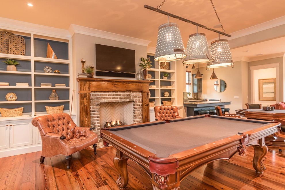 Photo of a mid-sized country open concept family room in Atlanta with a game room, grey walls, medium hardwood floors, a standard fireplace, a brick fireplace surround, a wall-mounted tv and brown floor.