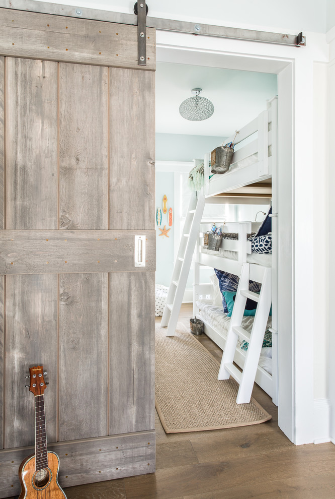 Photo of a mid-sized beach style gender-neutral kids' room in New York with blue walls and medium hardwood floors.
