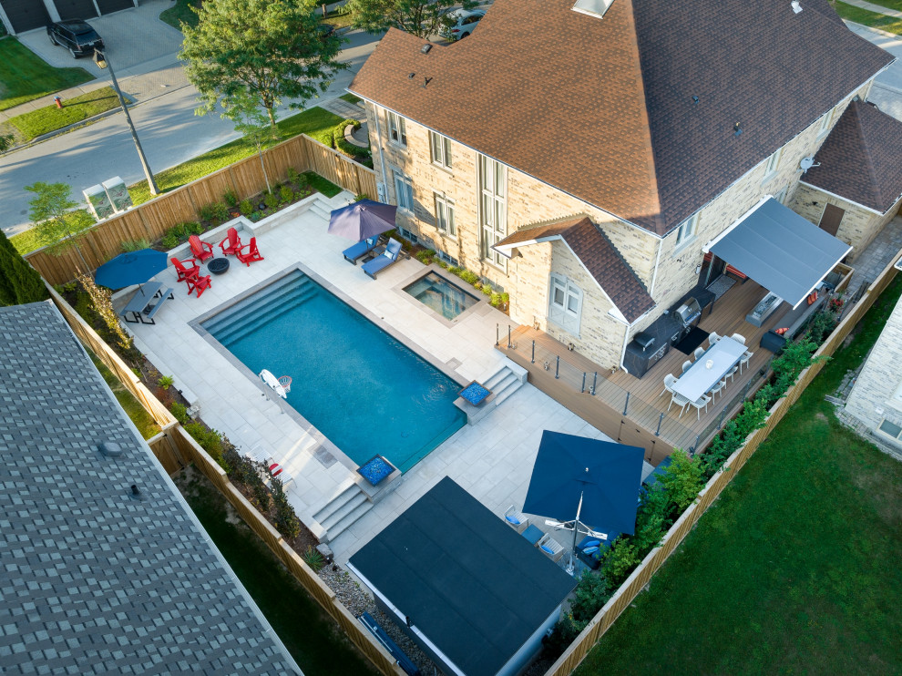 Mid-sized transitional backyard concrete paver and rectangular infinity pool landscaping photo in Toronto