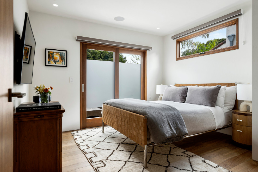 Diseño de habitación de invitados contemporánea pequeña sin chimenea con paredes blancas, suelo marrón y suelo de madera en tonos medios