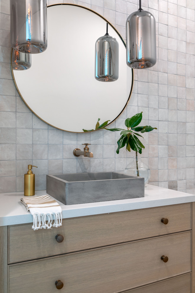 Photo of a large transitional powder room in Houston with light wood cabinets, gray tile, light hardwood floors, a drop-in sink, brown floor, a built-in vanity, ceramic tile and grey walls.
