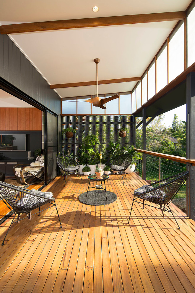 This is an example of a mid-sized contemporary backyard deck in Brisbane with a vertical garden and a roof extension.