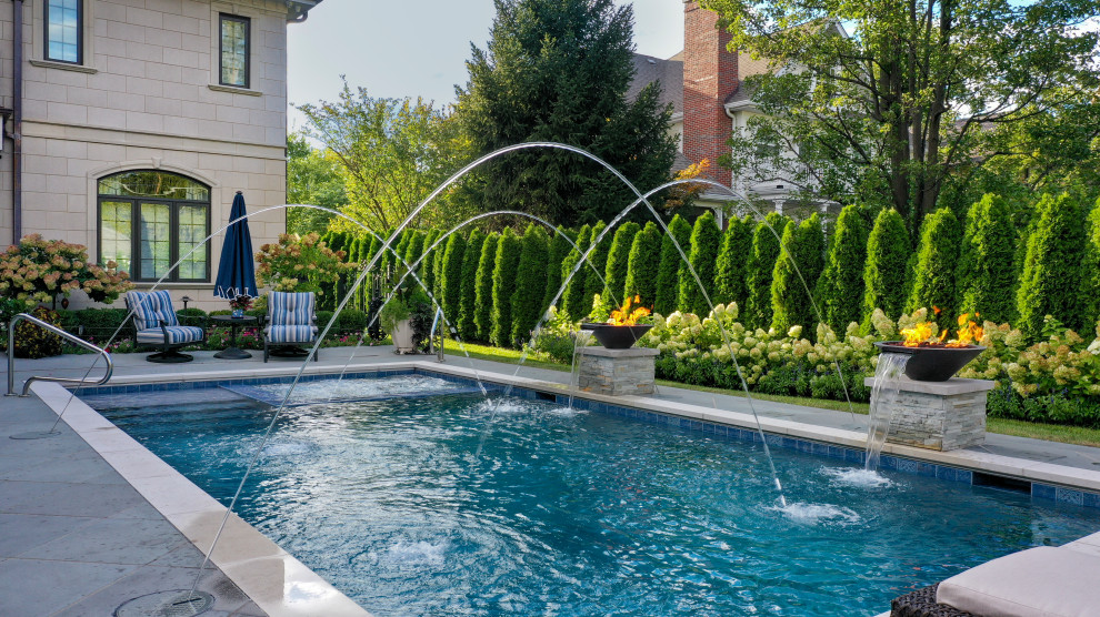 Imagen de piscina alargada clásica de tamaño medio rectangular en patio trasero con privacidad y adoquines de piedra natural
