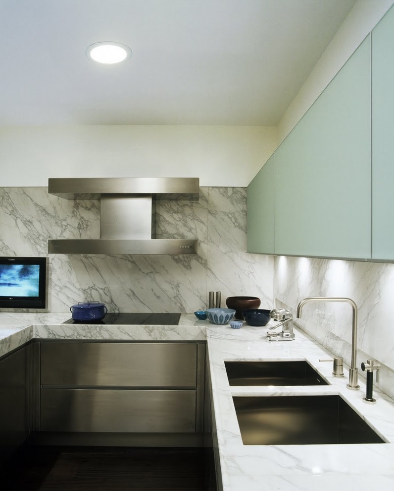 Photo of a modern kitchen in New York with marble benchtops, a double-bowl sink, flat-panel cabinets, stainless steel cabinets, white splashback and stone slab splashback.