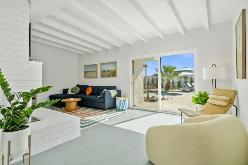 Esempio di un soggiorno minimalista con pareti bianche, pavimento in laminato, camino classico, cornice del camino in mattoni, TV a parete, pavimento blu e travi a vista