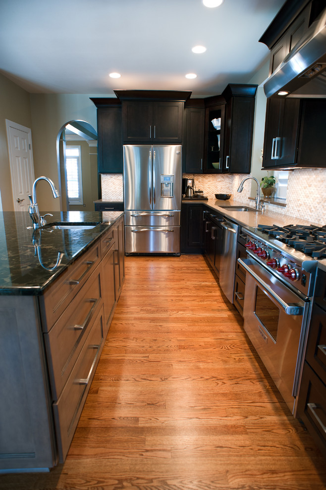 Example of a mid-sized transitional l-shaped kitchen design in Charlotte with dark wood cabinets, granite countertops, white backsplash and an island