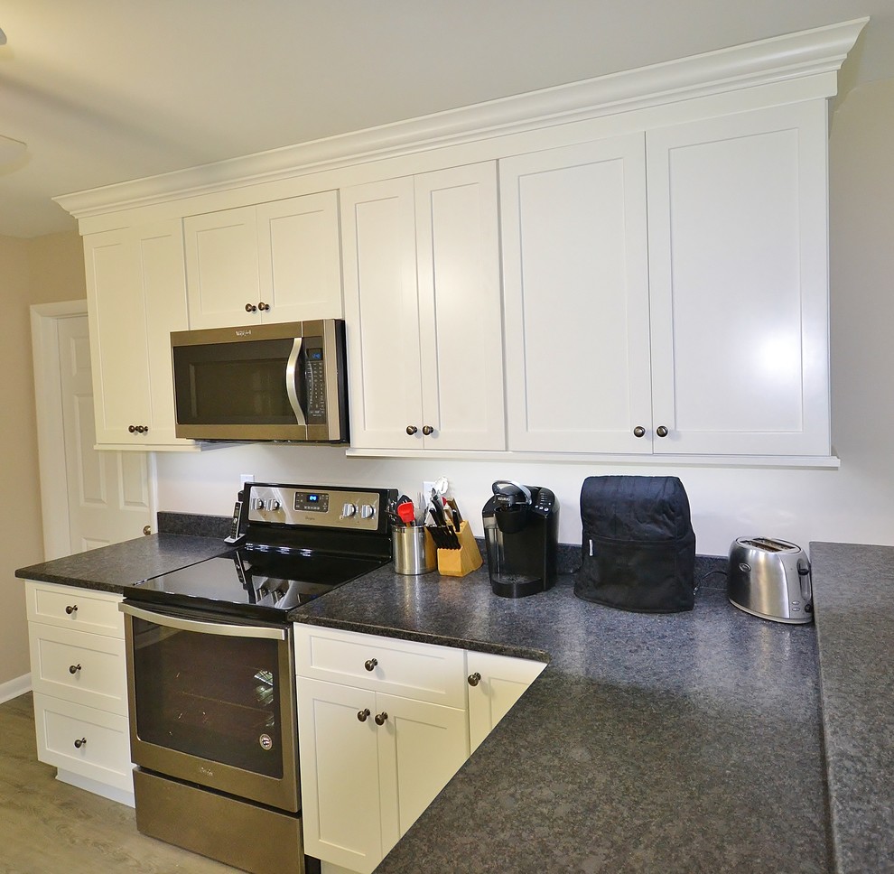 Photo of a mid-sized traditional galley eat-in kitchen in Philadelphia with an undermount sink, shaker cabinets, white cabinets, granite benchtops, stainless steel appliances, linoleum floors, beige floor and a peninsula.