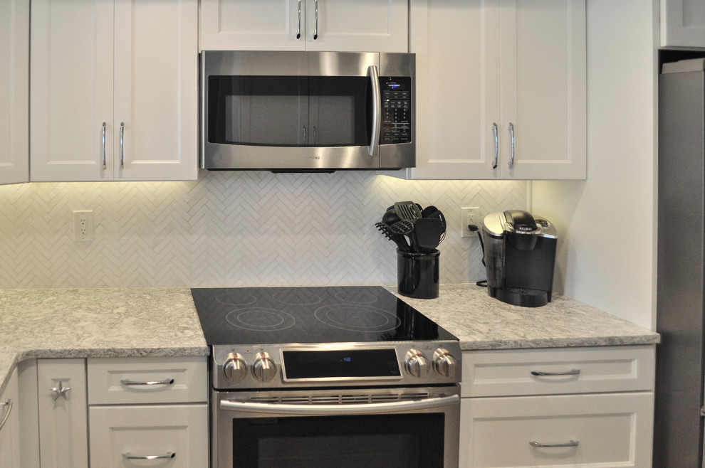 Eat-in kitchen - mid-sized transitional u-shaped eat-in kitchen idea with an undermount sink, shaker cabinets, white cabinets, quartz countertops, white backsplash, marble backsplash, stainless steel appliances and no island