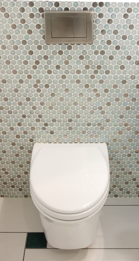 Diseño de aseo contemporáneo de tamaño medio con lavabo sobreencimera, encimera de vidrio reciclado, sanitario de pared y baldosas y/o azulejos multicolor