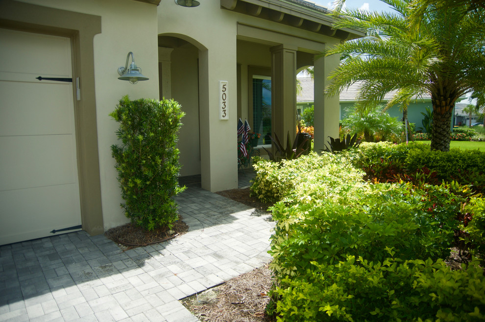 Photo of a tropical front yard full sun driveway in Miami with concrete pavers.