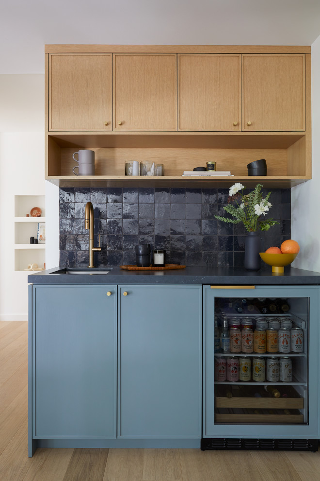 Inspiration for a small 1950s single-wall light wood floor and brown floor wet bar remodel in San Francisco with an undermount sink, shaker cabinets, blue cabinets, soapstone countertops, gray backsplash, terra-cotta backsplash and black countertops
