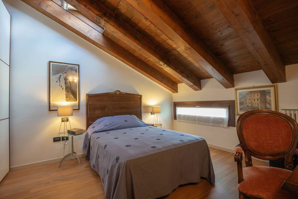 Ejemplo de dormitorio principal ecléctico de tamaño medio con paredes blancas, suelo de madera clara y vigas vistas
