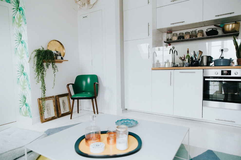 Inspiration for a mid-sized contemporary l-shaped open plan kitchen in Paris with beaded inset cabinets, stainless steel cabinets, wood benchtops, white splashback, stainless steel appliances, ceramic floors, with island and white floor.