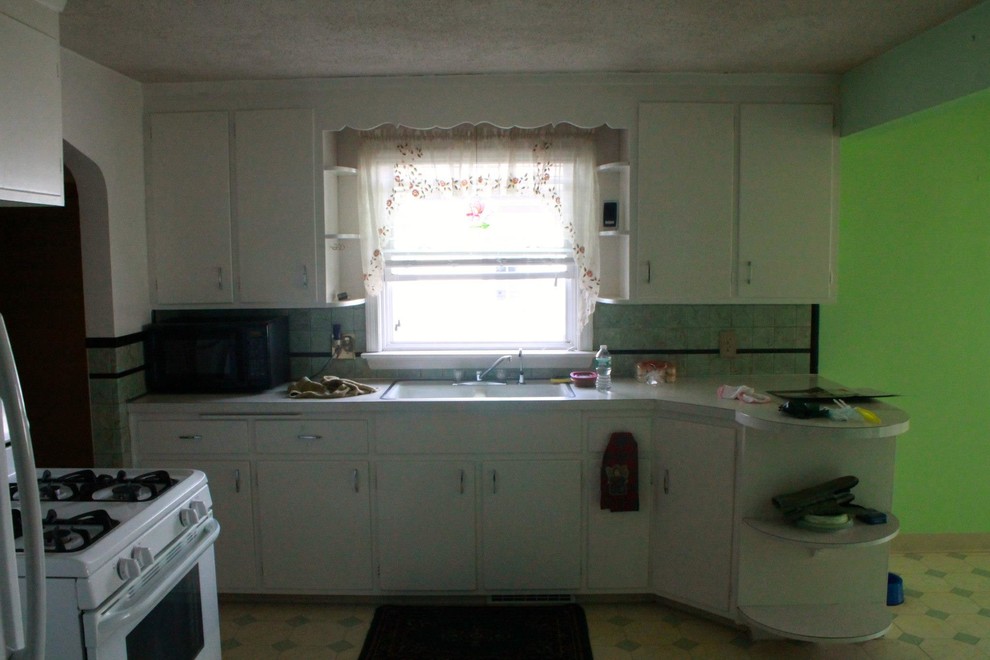 Example of a mid-sized minimalist l-shaped medium tone wood floor eat-in kitchen design with a double-bowl sink, shaker cabinets, white cabinets, laminate countertops, beige backsplash, stone tile backsplash, white appliances and a peninsula