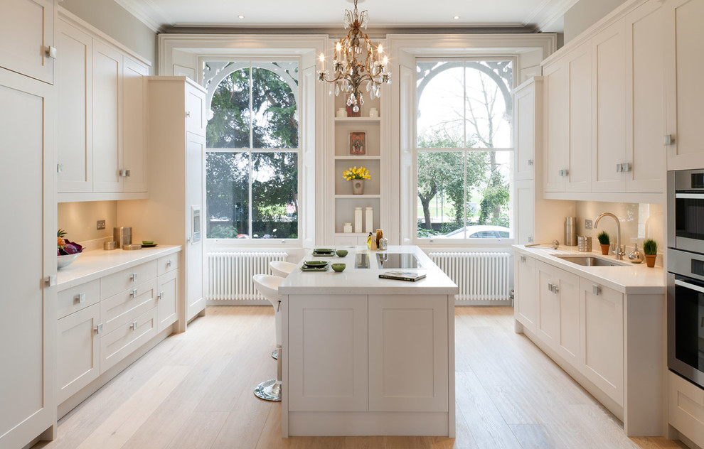Photo of a traditional separate kitchen in London with shaker cabinets, light hardwood floors and with island.