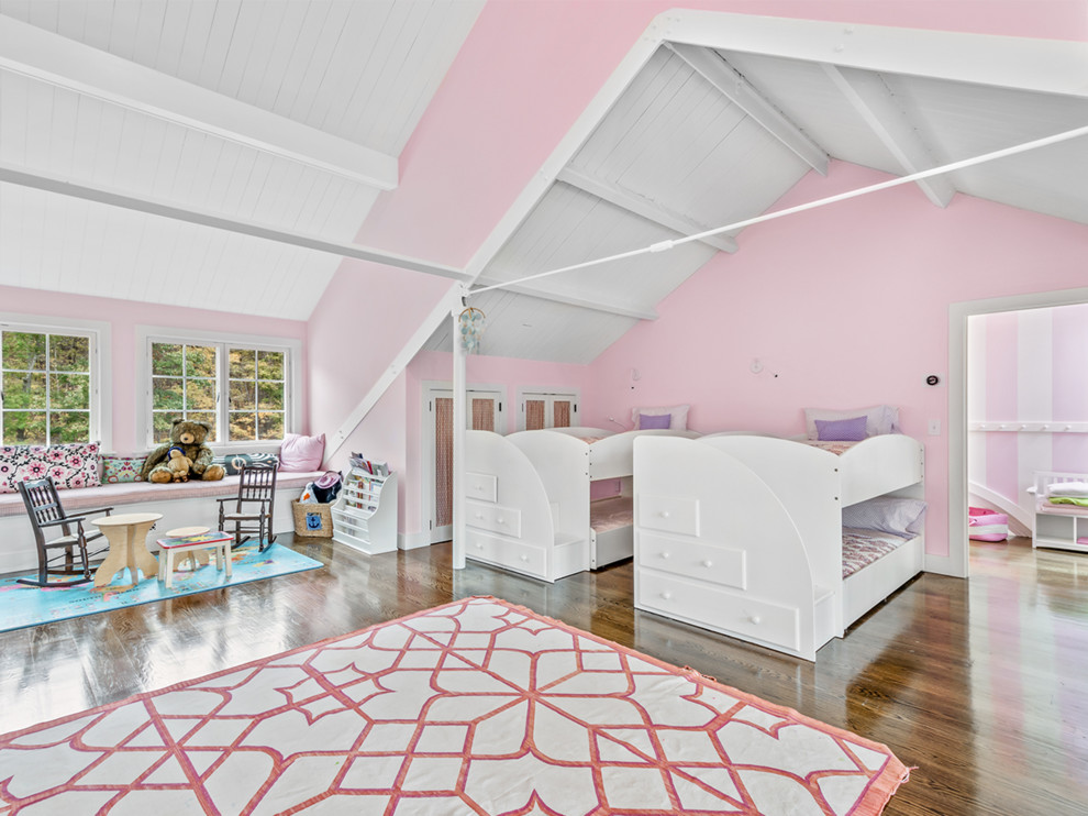 This is an example of a country kids' bedroom for girls in New York with pink walls, dark hardwood floors and brown floor.