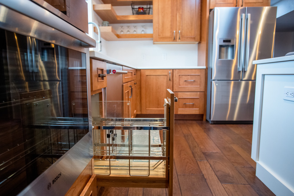Example of a mid-sized l-shaped dark wood floor and brown floor eat-in kitchen design with an undermount sink, shaker cabinets, white cabinets, quartz countertops, stainless steel appliances, an island and white countertops