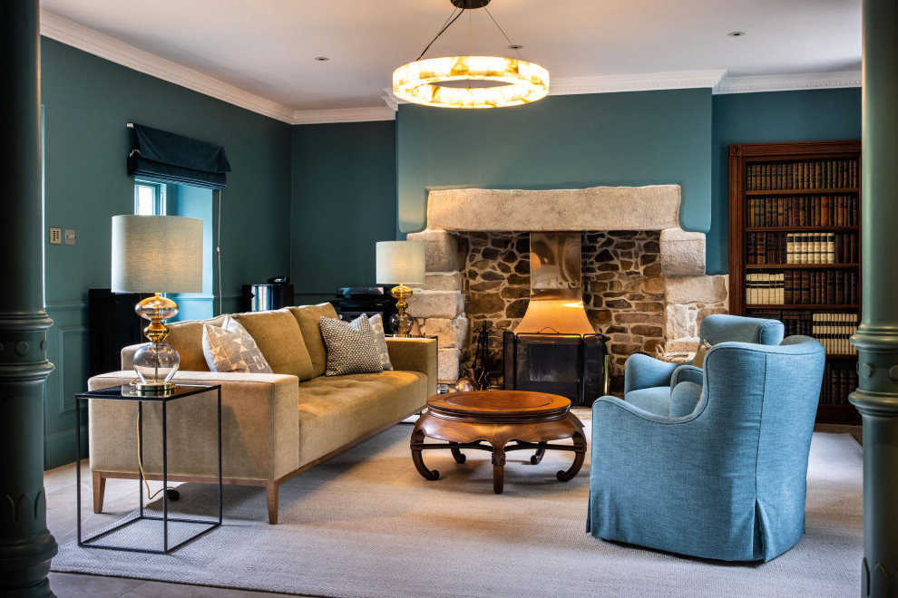 Пример оригинального дизайна: изолированная гостиная комната в стиле кантри с синими стенами, печью-буржуйкой, фасадом камина из камня, бежевым полом и панелями на части стены без телевизора
