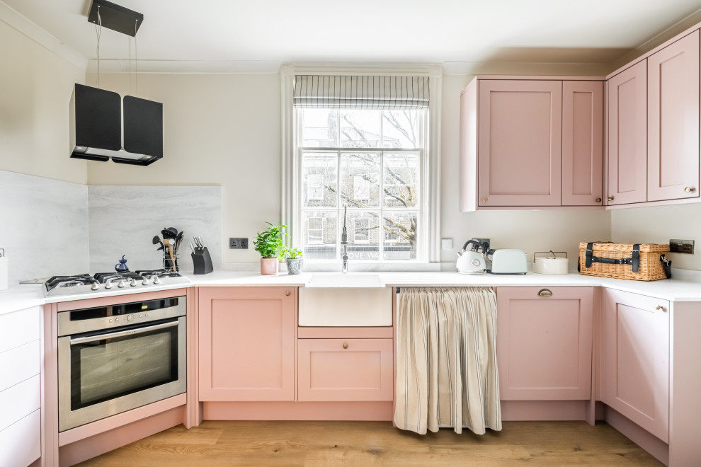 Exemple d'une cuisine éclectique de taille moyenne avec un placard à porte shaker, des portes de placard rose, un plan de travail en surface solide et un plan de travail blanc.