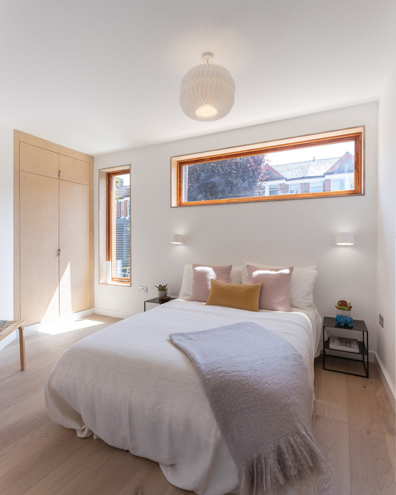 Mid-sized contemporary master bedroom in London with white walls, light hardwood floors and beige floor.