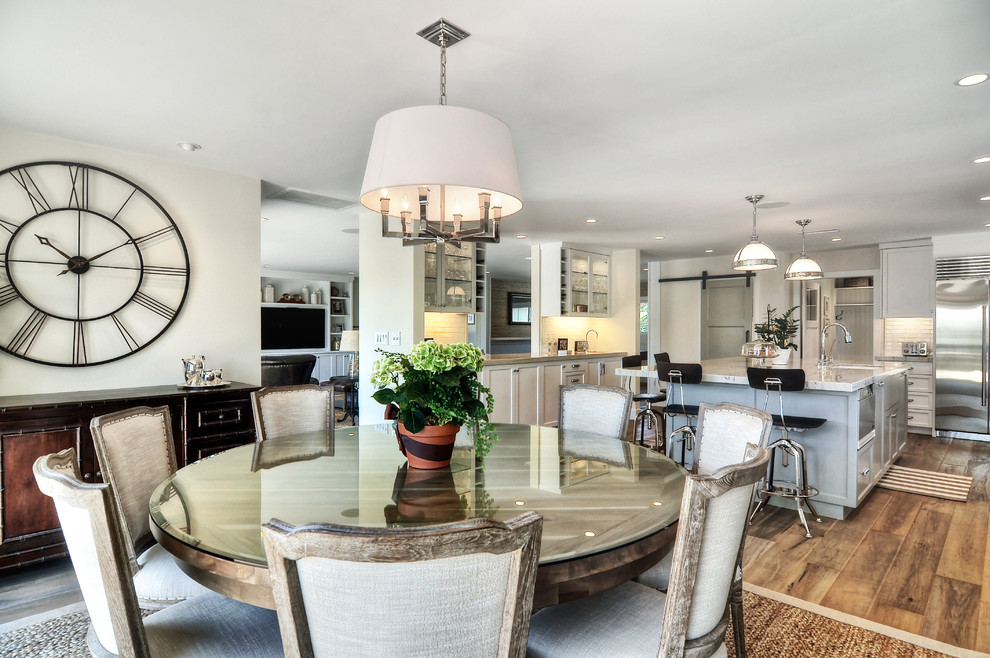 Eat-in kitchen - mid-sized transitional l-shaped medium tone wood floor and brown floor eat-in kitchen idea in Orange County with white walls, no fireplace, an undermount sink, recessed-panel cabinets, white cabinets, quartzite countertops, white backsplash, subway tile backsplash, stainless steel appliances, an island and white countertops