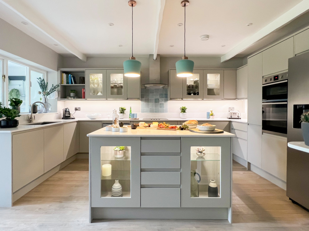 Photo of a mid-sized country u-shaped open plan kitchen in Gloucestershire with an integrated sink, flat-panel cabinets, grey cabinets, solid surface benchtops, panelled appliances, vinyl floors, with island, white benchtop and exposed beam.