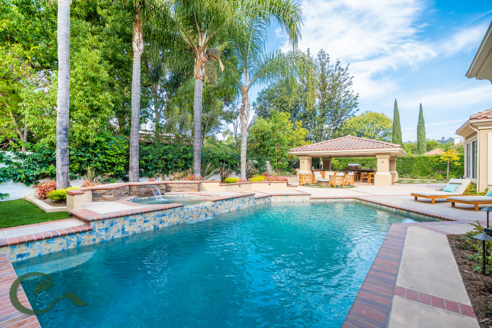 Photo of a mid-sized mediterranean backyard custom-shaped lap pool in Orange County with a water feature and concrete slab.