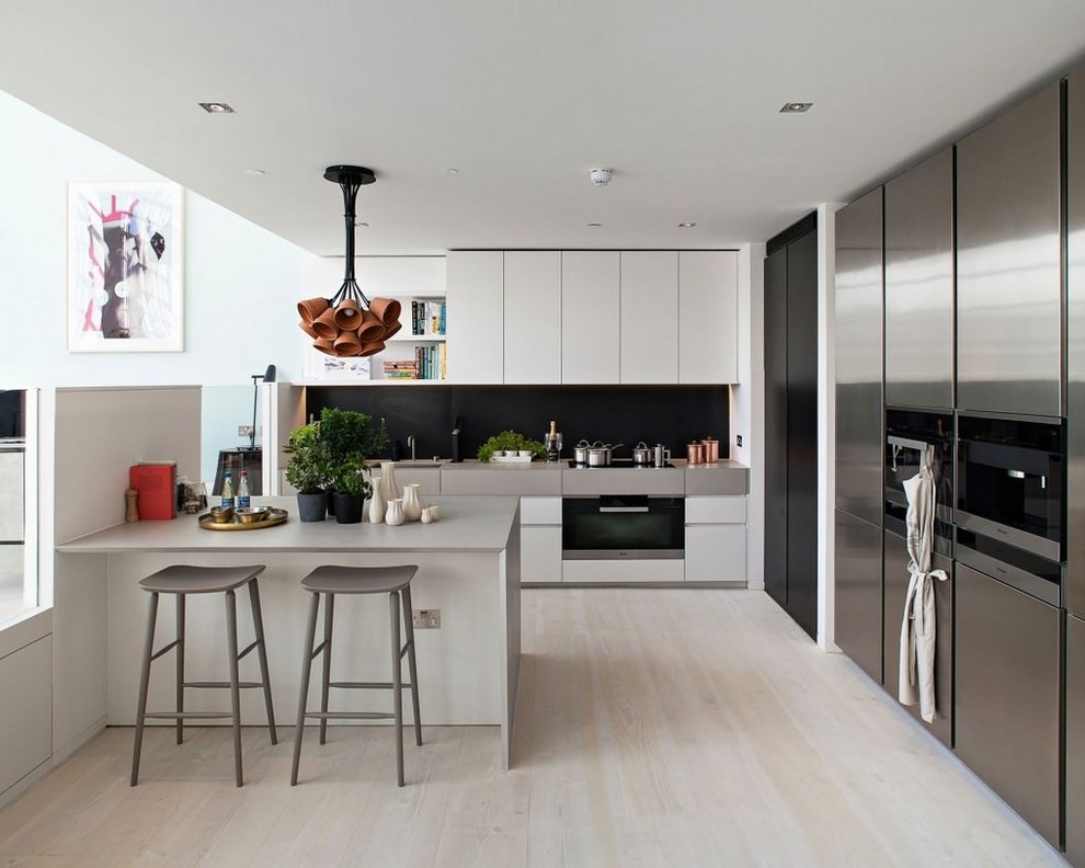 This is an example of a large transitional l-shaped eat-in kitchen in Madrid with flat-panel cabinets, white cabinets, stainless steel appliances, light hardwood floors, black splashback, a peninsula and grey benchtop.