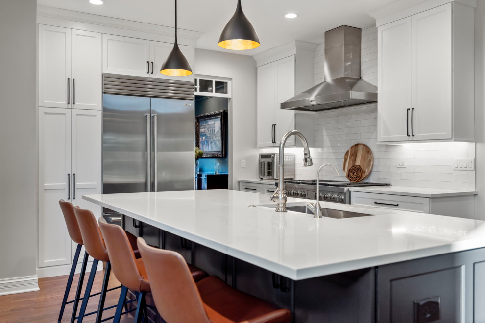 Mid-sized transitional l-shaped kitchen photo in Chicago with an undermount sink, shaker cabinets, quartz countertops, white backsplash, ceramic backsplash, stainless steel appliances, an island and white countertops