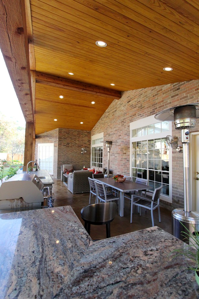 This is an example of a country backyard patio in Houston with an outdoor kitchen and a roof extension.