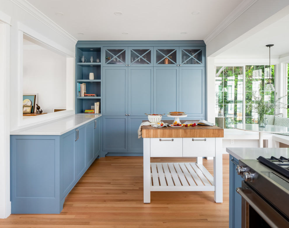 This is an example of a mid-sized transitional galley separate kitchen in Vancouver with an undermount sink, shaker cabinets, blue cabinets, quartz benchtops, white splashback, subway tile splashback, stainless steel appliances, light hardwood floors, no island, beige floor and grey benchtop.