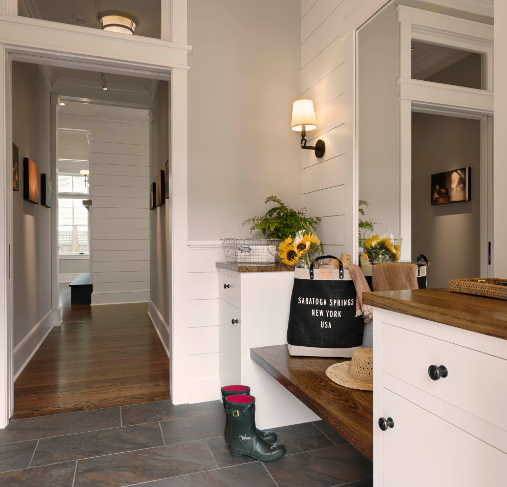 Mid-sized transitional mudroom with grey walls, grey floor and planked wall panelling.