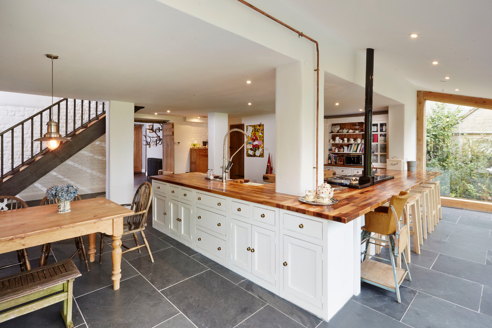 Large country l-shaped eat-in kitchen in Wiltshire with a farmhouse sink, shaker cabinets, white cabinets, wood benchtops, panelled appliances and no island.